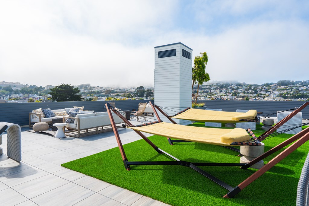 a roof top deck with lounge chairs and a hammock