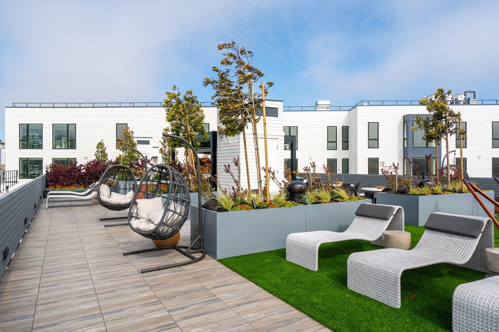 a roof terrace with white wicker chairs and green grass