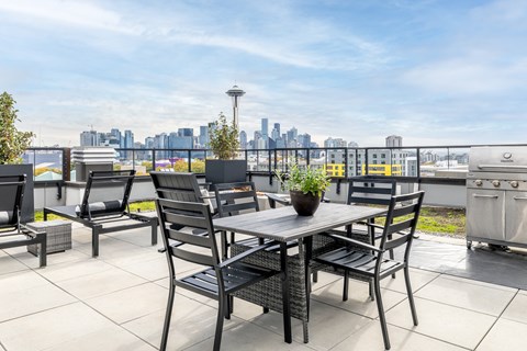 A patio with a table and chairs overlooking a city skyline.