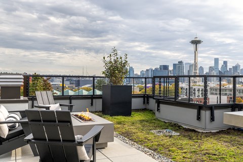 A patio with chairs and a table overlooking a city skyline.