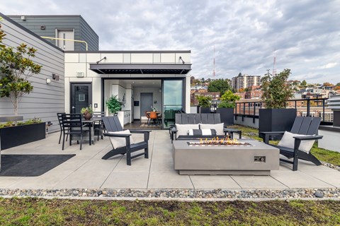 A modern outdoor patio with a fire pit and seating area.