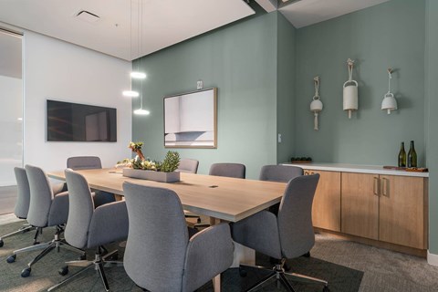 A conference room with a long table and grey chairs.