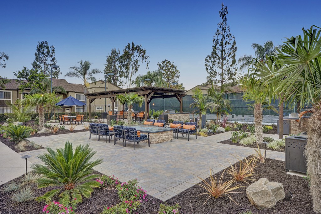 A patio with a table and chairs surrounded by plants.