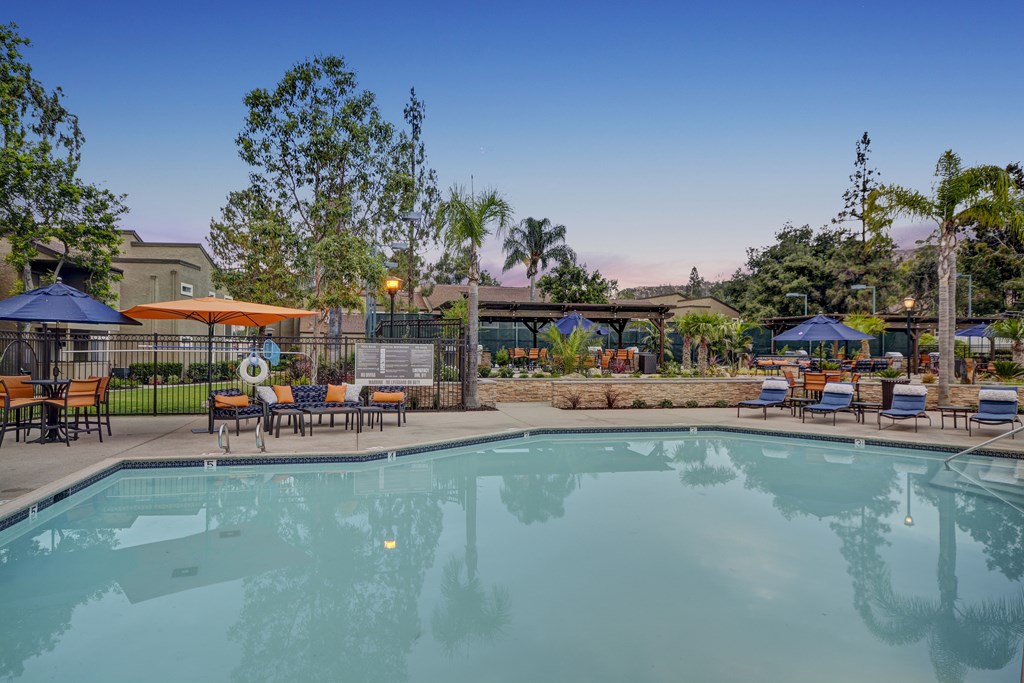 A large swimming pool surrounded by lounge chairs and umbrellas.