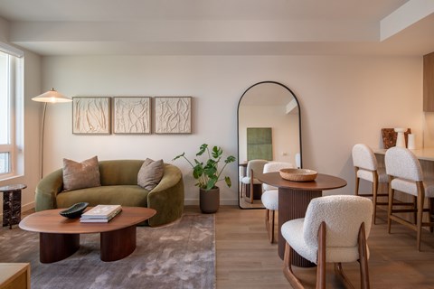 A living room with a green couch, a round table, and a mirror.
