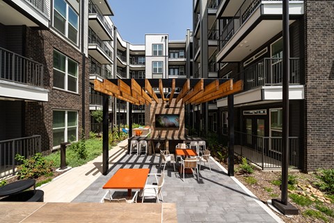 an outdoor patio area with tables and chairs and an apartment building