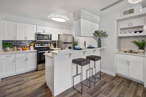 A kitchen with white cabinets and a bar area.