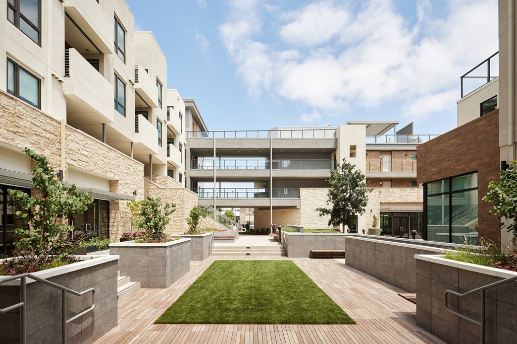 a courtyard with grass and trees in front of an apartment building