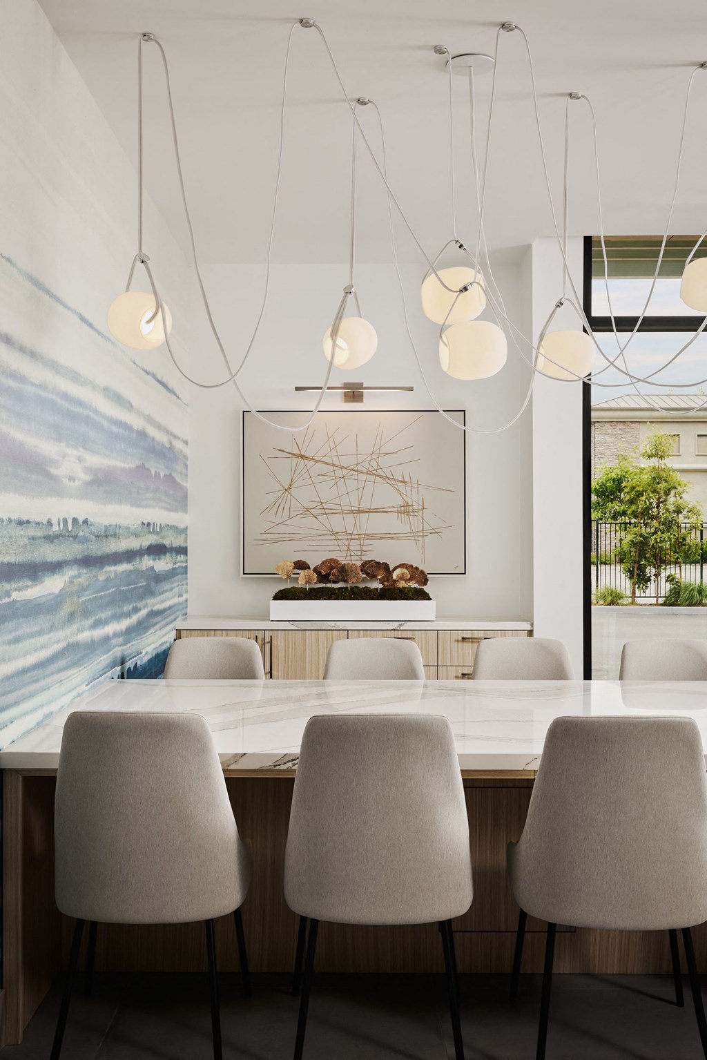 a long table with white chairs and a large painting on the wall