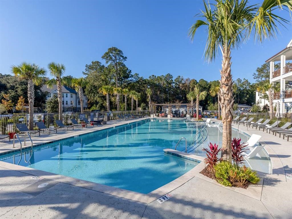 a large swimming pool with chairs and palm trees