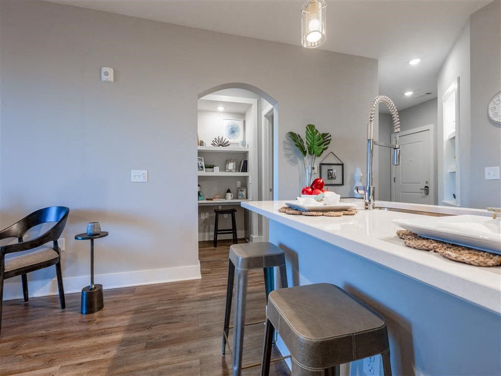 a kitchen with a counter and stools next to a living room