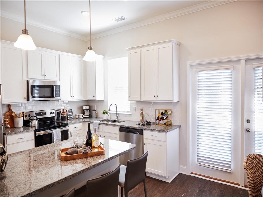 a kitchen with white cabinets and a marble counter top