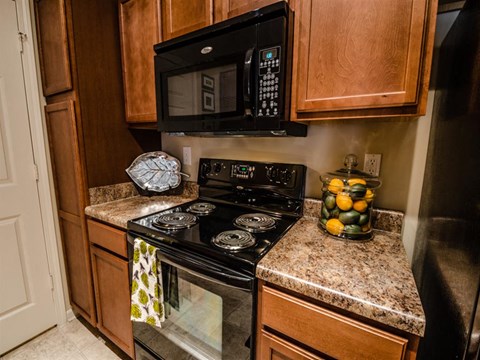 A black microwave oven is mounted above a black stove in a kitchen.