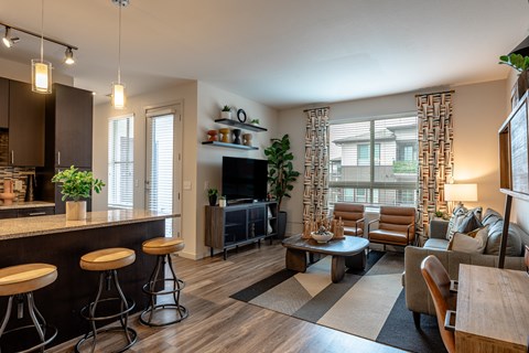 A modern living room with a bar area and a large window.