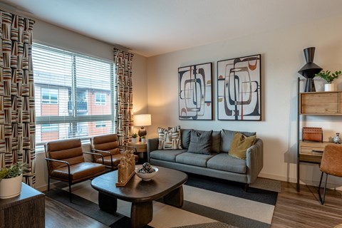 A living room with a grey couch, a brown chair, a coffee table, and a painting on the wall.