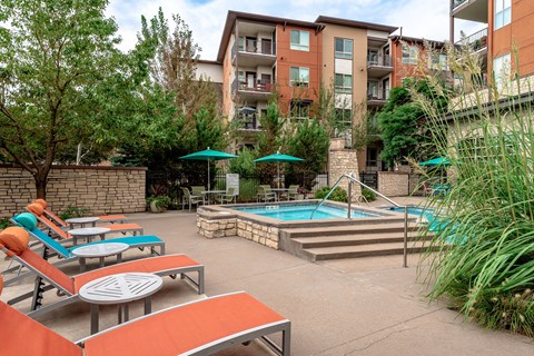 A pool area with sun loungers and umbrellas in front of a building.