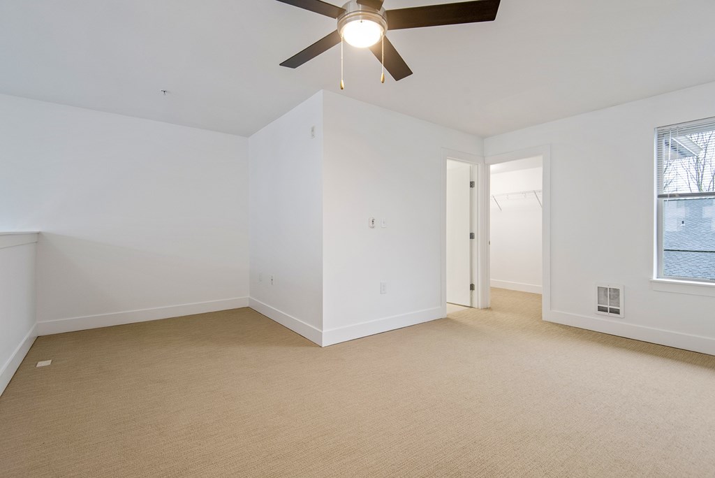 A room with a ceiling fan and carpeted floor.