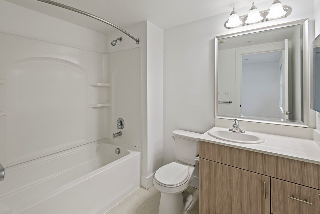 A white bathroom with a tub, toilet, sink, and mirror.