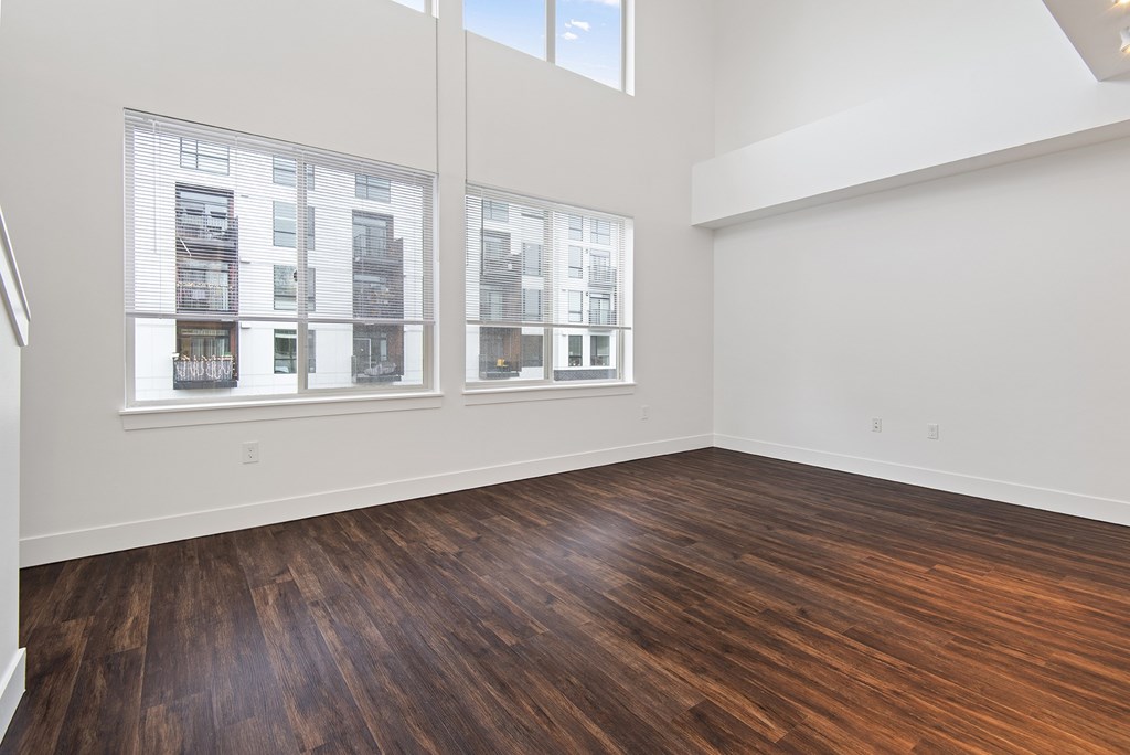 A room with wooden floors and windows showing a view of a building outside.