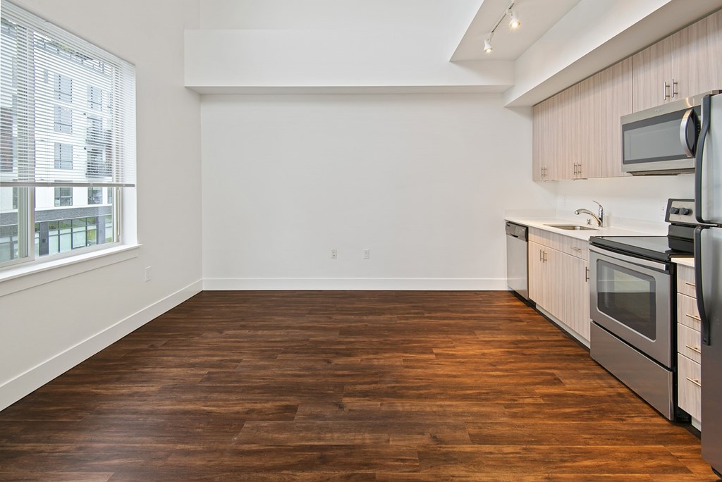 A kitchen with white cabinets and a wooden floor.