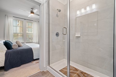 A bedroom with a bed and a glass shower door.