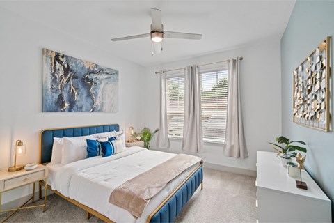 A bedroom with a large bed and a ceiling fan.