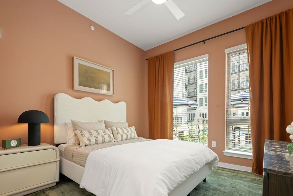 A bedroom with a large bed, a nightstand with a lamp, and a painting on the wall.