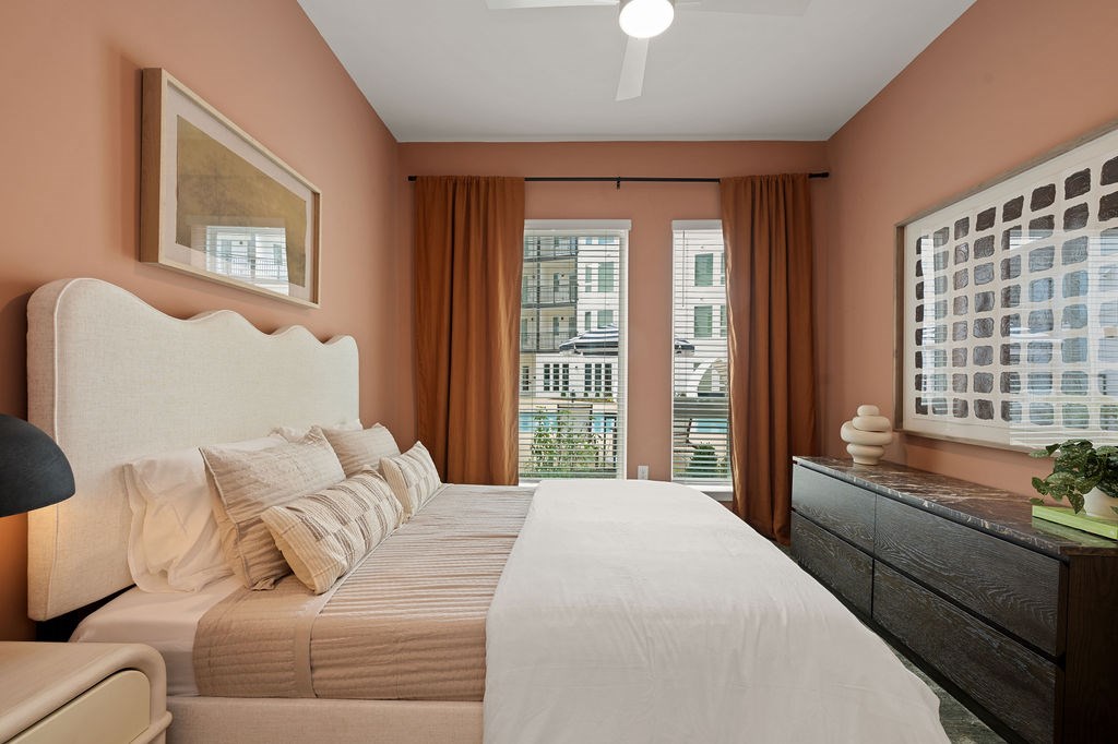 A bedroom with a large bed, a nightstand, and a window with curtains.