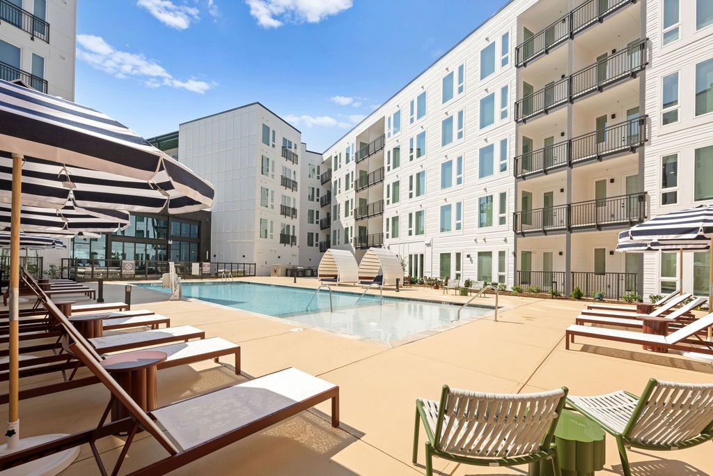 A sunny day at the pool with chairs and umbrellas.