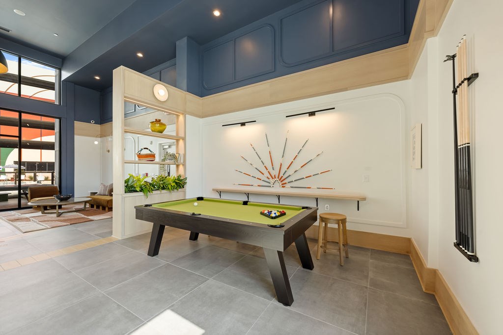 A pool table with a green felt cloth and a billiard ball rack is in the middle of the room.