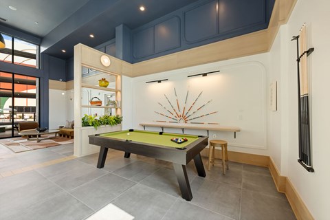 A pool table with a green felt cloth and a billiard ball rack is in the middle of the room.