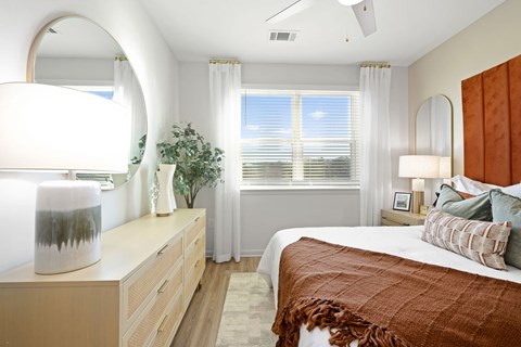 A bedroom with a bed, nightstand, and a window with blinds.