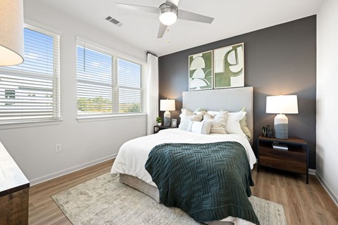 A bedroom with a bed, two lamps, and a ceiling fan.