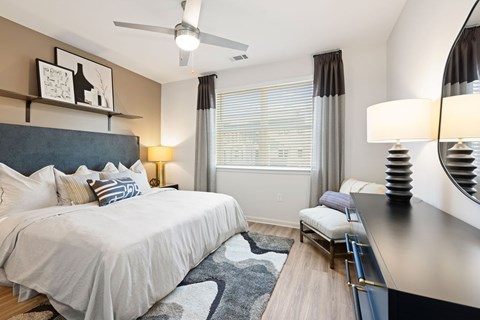 A bedroom with a large bed and a mirrored dresser.