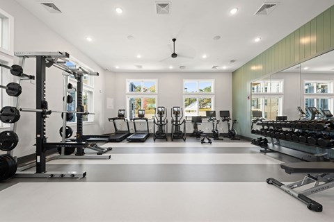 A spacious gym with a variety of equipment including a weight bench, treadmill, and exercise bikes.