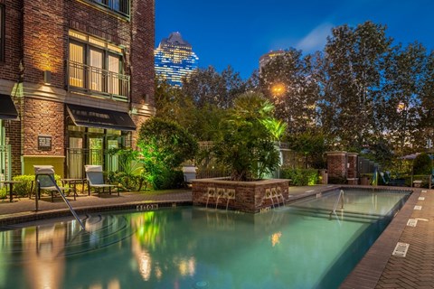 a swimming pool with a city in the background at night