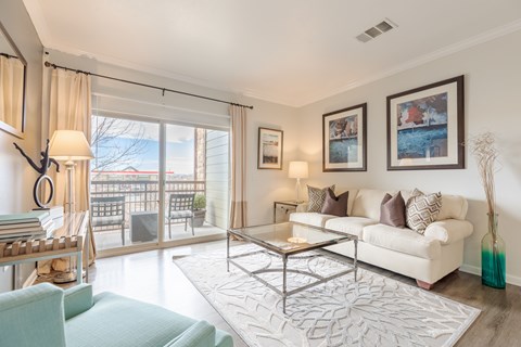 A living room with a white couch and a glass table.