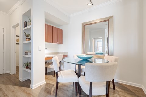A dining room with a glass table and white chairs.