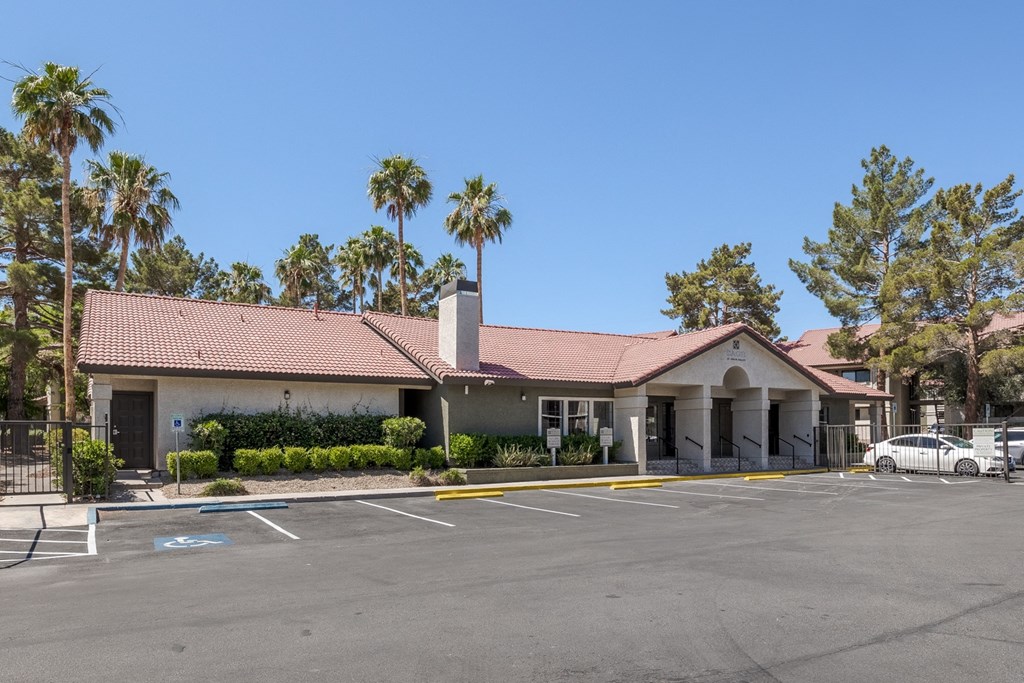 an empty parking lot in front of a building with palm trees