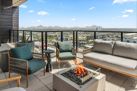 Exterior patio with a fire pit and seating area overlooking a cityscape.