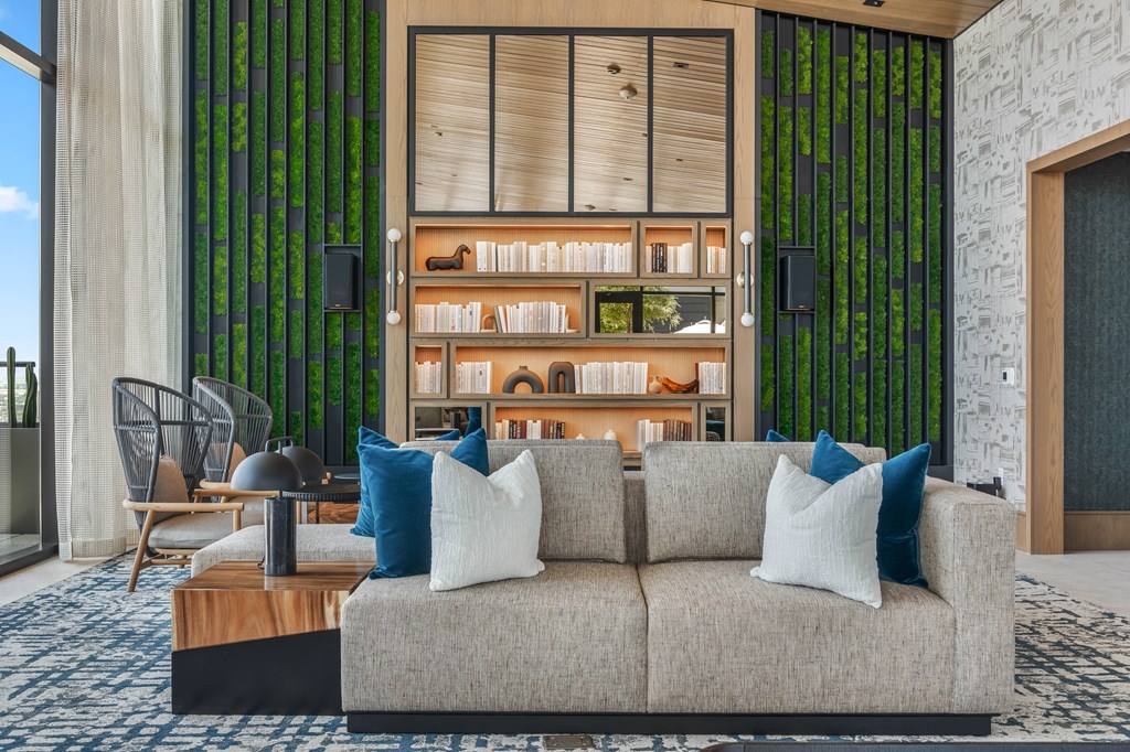 A modern living room with a grey couch and a wooden bookshelf.