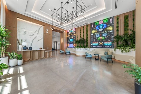 Exterior modern lobby with a large neon wall and plants.