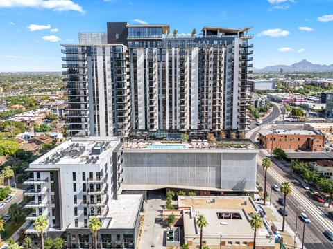 A modern multi-story building with a parking garage in front.