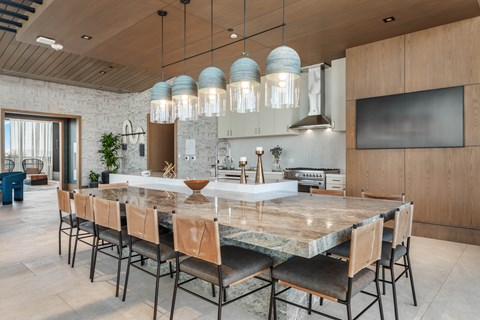 A modern kitchen in the clubroom with a marble island and bar stools.