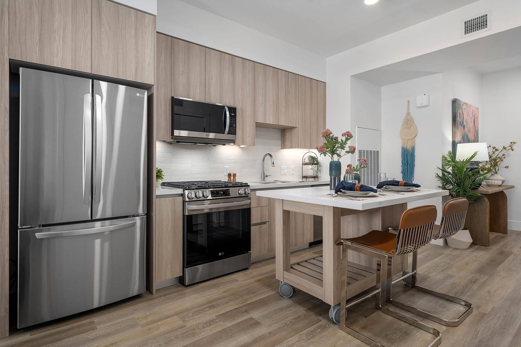 A modern kitchen with a stainless steel refrigerator and a wooden island.