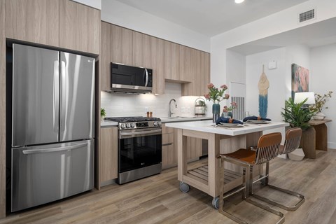 A modern kitchen with a stainless steel refrigerator and a wooden island.