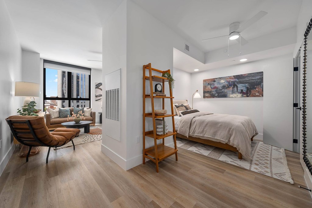 A bedroom with a bed, chair, and a painting on the wall.