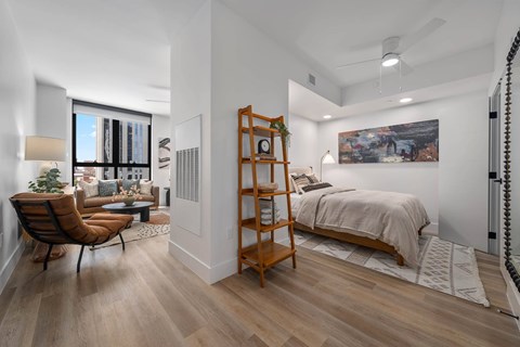 A bedroom with a bed, chair, and a painting on the wall.
