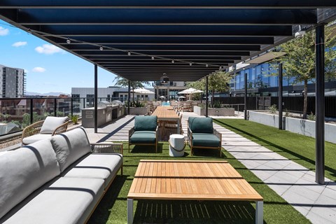 A patio with a wooden table and chairs under a roof.
