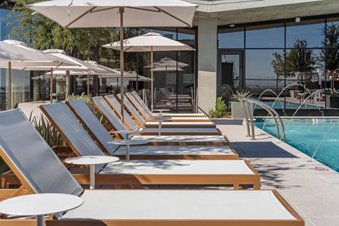 Outdoor lounge seating by the pool with umbrellas.